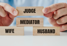 Blocks labeled with wife and husband have a "mediator" block in between them. A person's hands hover a "judge" block over them.