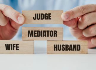 Blocks labeled with wife and husband have a "mediator" block in between them. A person's hands hover a "judge" block over them.
