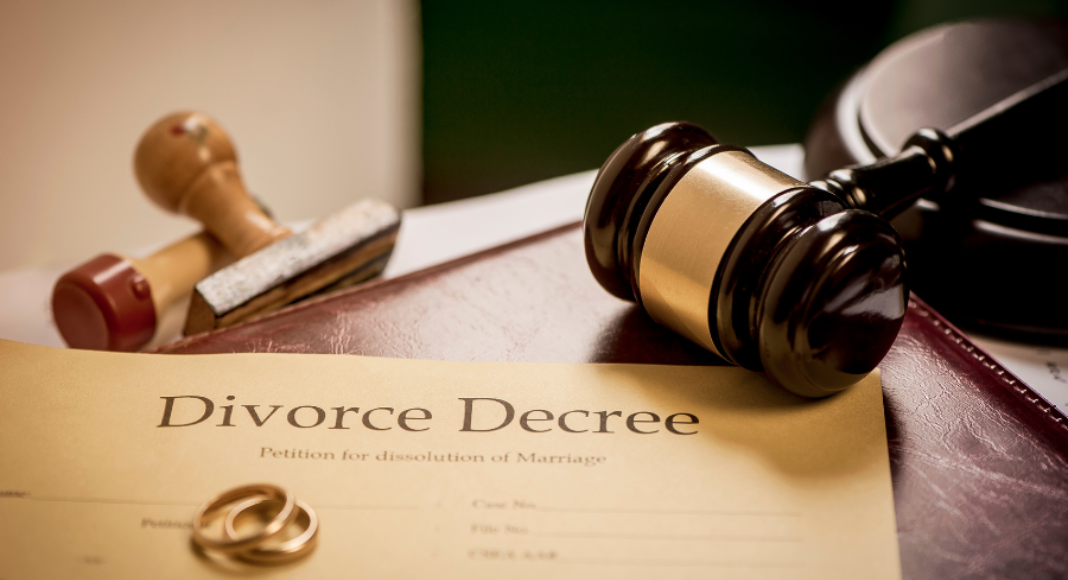 Divorce process: a divorce decree sits on a table, with rings on top and a gavel next to it.
