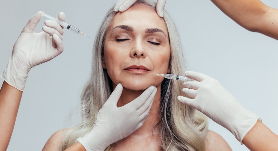 An older woman getting injections in her face.