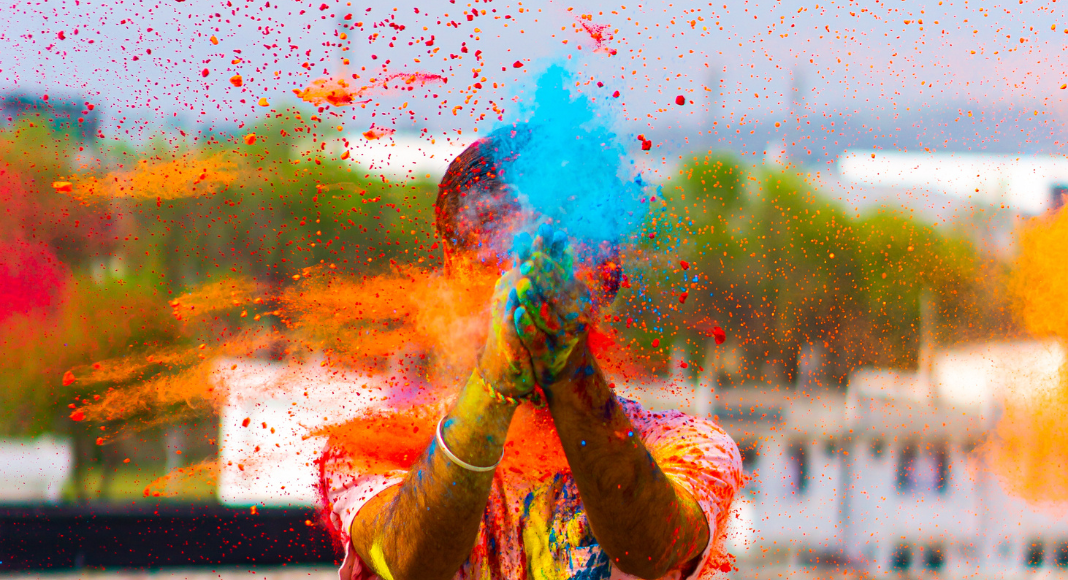 A person slapping colored powders together in their hands, celebrating Holi.