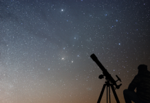 National Space Day: a silhouette of a person with a telescope set up to view the starry night.