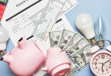 reduce monthly spending: a piggy bank broken open among a pile of cash, bills, light bulbs, clock, and calculator.