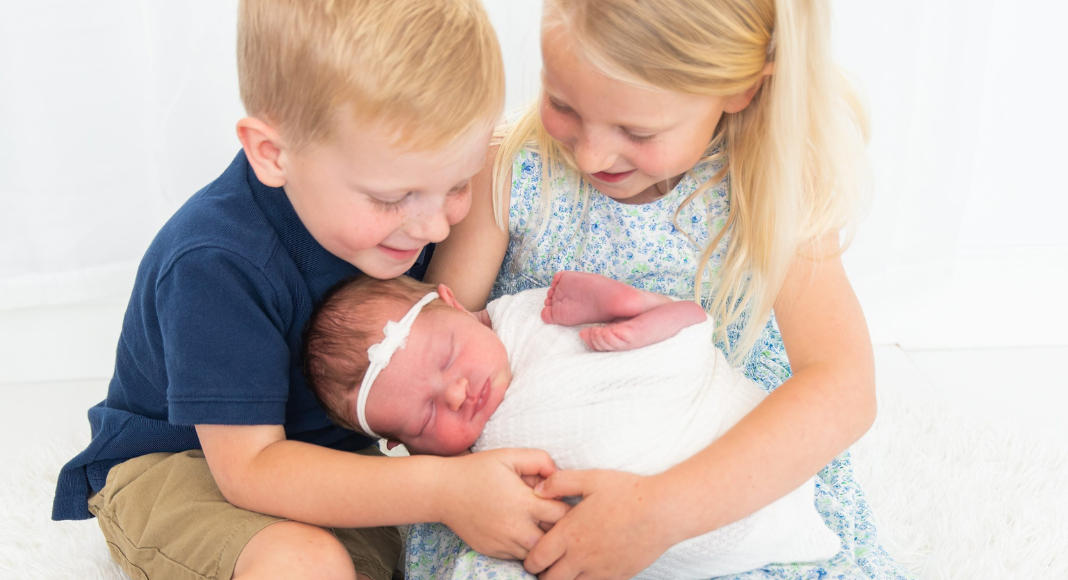 Third Child: two toddlers hold their baby sister.