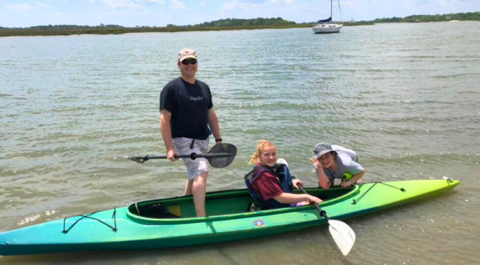 Things to do in Charleston with teens: a dad and his two teenagers pose in a kayak on the water.