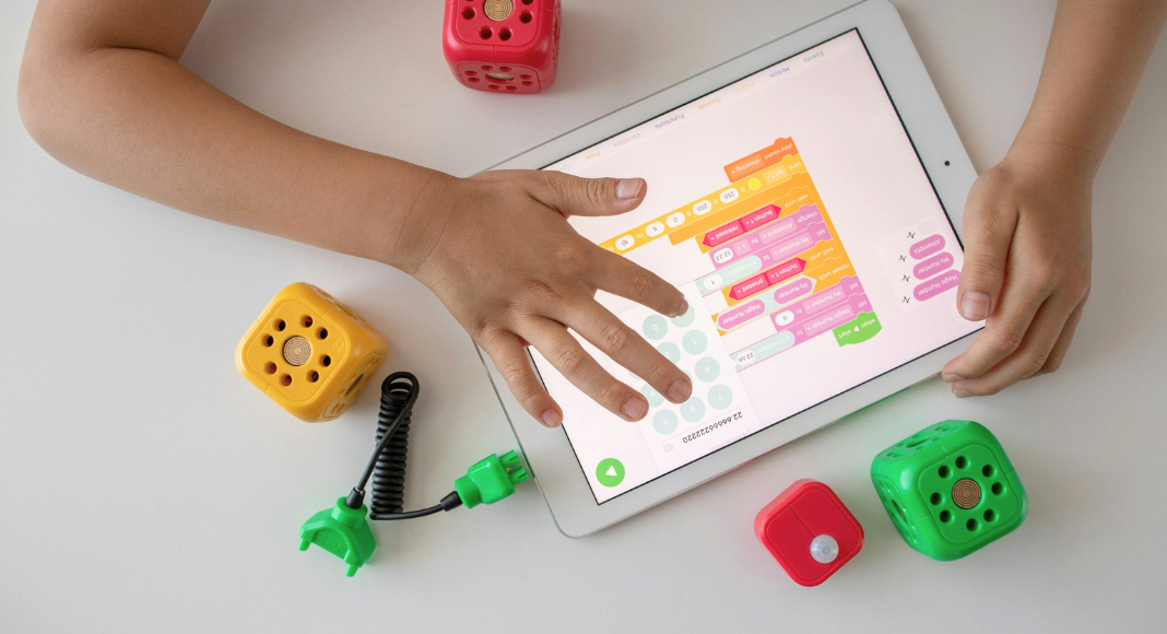 A child's hands play with a STEM program on a tablet.