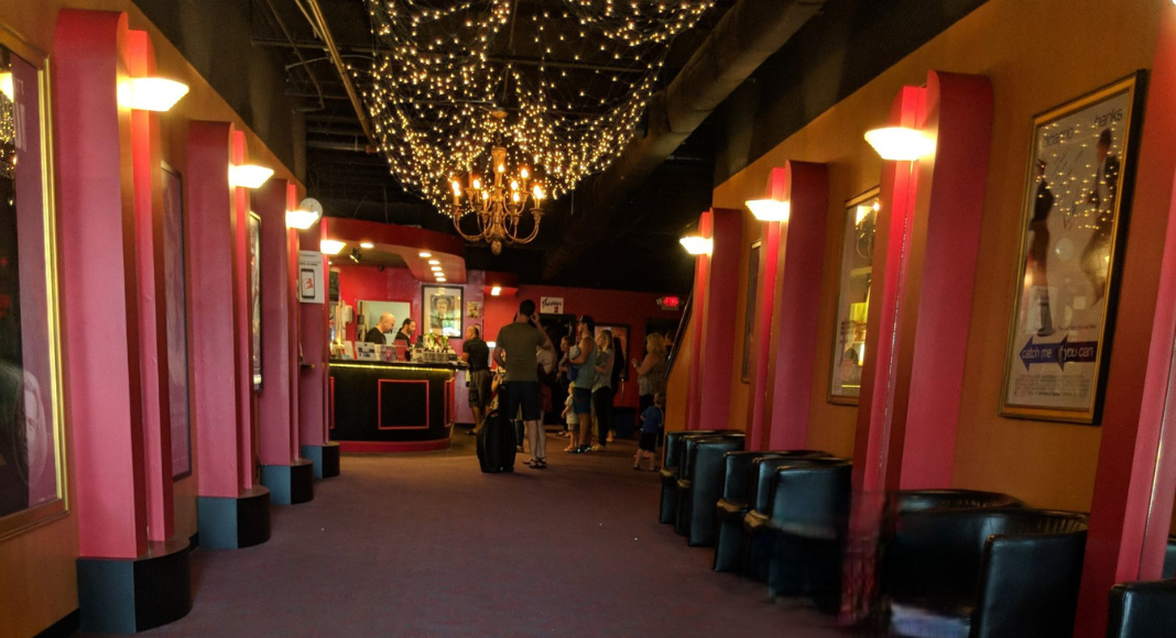 Terrace movie theater from the inside: red walls and lit up pillars with with twinkle lights and chandeliers on the ceiling.