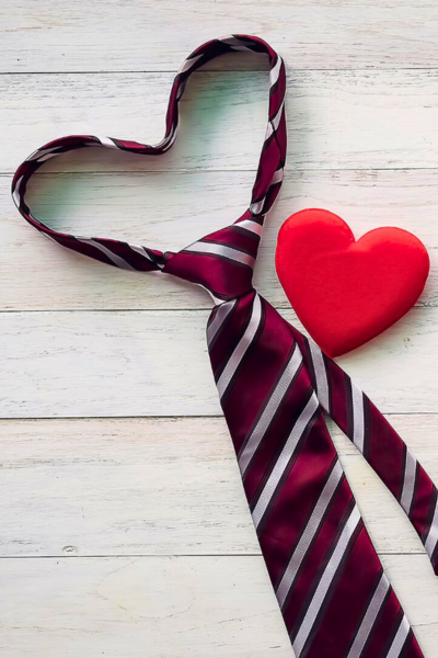 A red striped tie in the shape of a heart, next to a red clay heart.